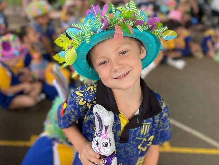 A boy with a playful bunny hat smiles at the camera.