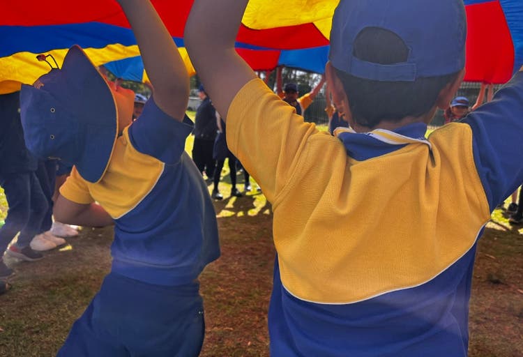 wo children proudly lift a colorful kite, enjoying a sunny day